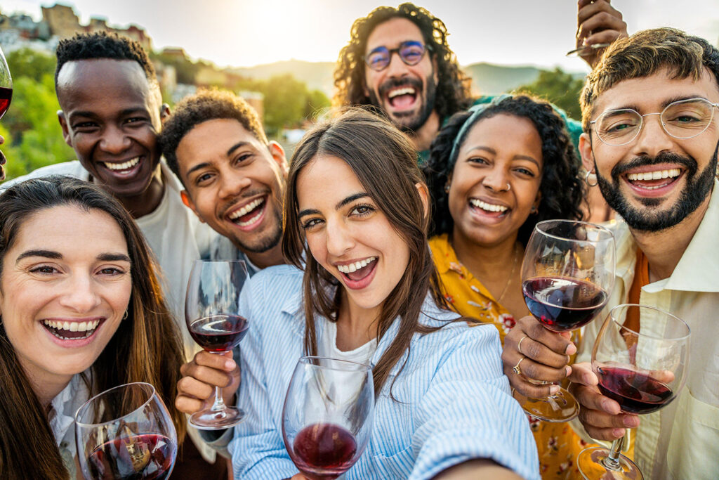 multiracial friend drinking win outside at festival