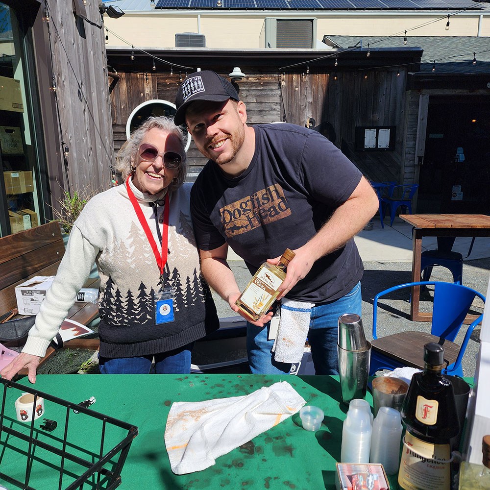 Mike Weinacht, assisted by volunteer Jane Harrah, displays Dogfish’s own special ingredient for the delicious PB-Tini he created for the Dogfish chocolate entry.