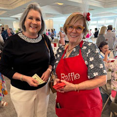 Sandy McNeil (in red) selling tickets to a guest who is hoping to win one of the many beautiful silent auction baskets.